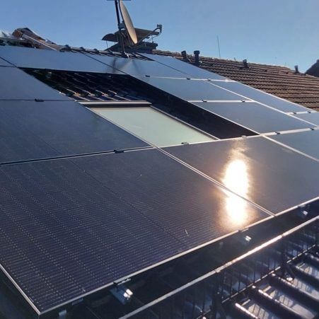 Photovoltaik, PV-Anlage, Dachinstallation Solaranlage auf einem Dach unter klarem Himmel mit reflektierendem Sonnenlicht.